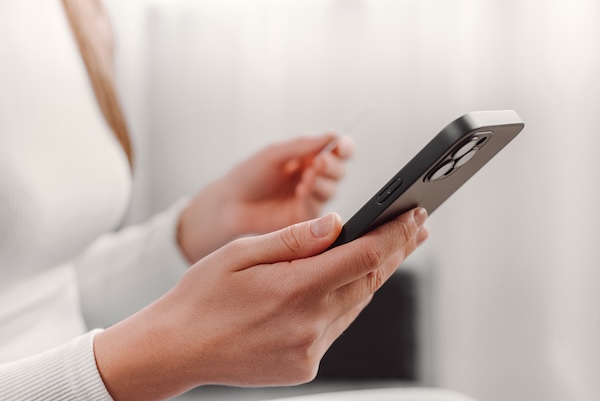 Close up of female hands holding credit card and smartphone sitting on sofa, paying online, using banking service, entering information, shopping, ordering in internet store, doing secure payment smart technology being used iphone female landlord